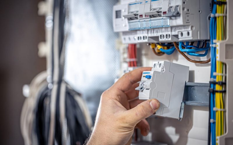 male-electrician-works-switchboard-with-electrical-connecting-cable